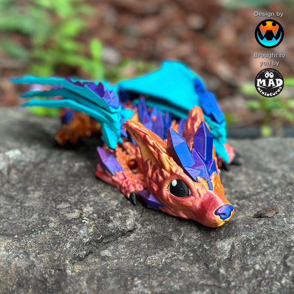 Baby Crystal Wolf Dragon sitting on a rock, its shimmering body and turquoise wings on full display. A magical addition to any fantasy collection.