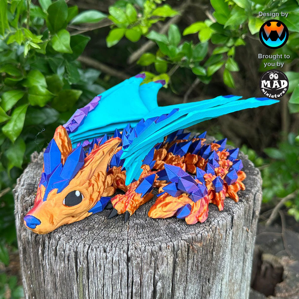 Baby Crystal Wolf Dragon from Mad Miniatures, designed by Cinderwing, sitting on a tree trunk with shimmering bronze/copper body and blue/magenta crystals.