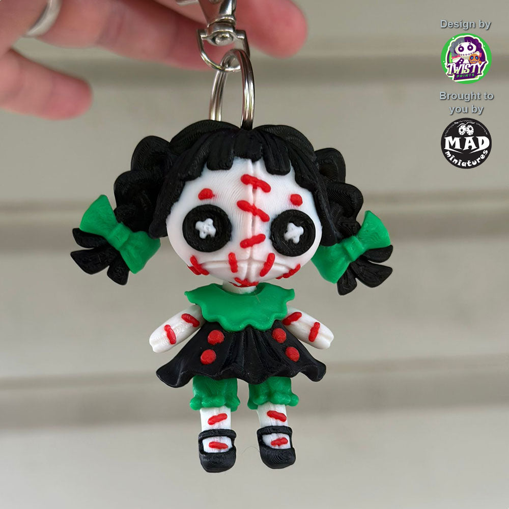 Close-up of the Creepy Doll Keychain from Mad Miniatures, designed by Twisty Prints. Featuring detailed facial expressions and a creepy yet charming look, this keychain is a must-have collectible.