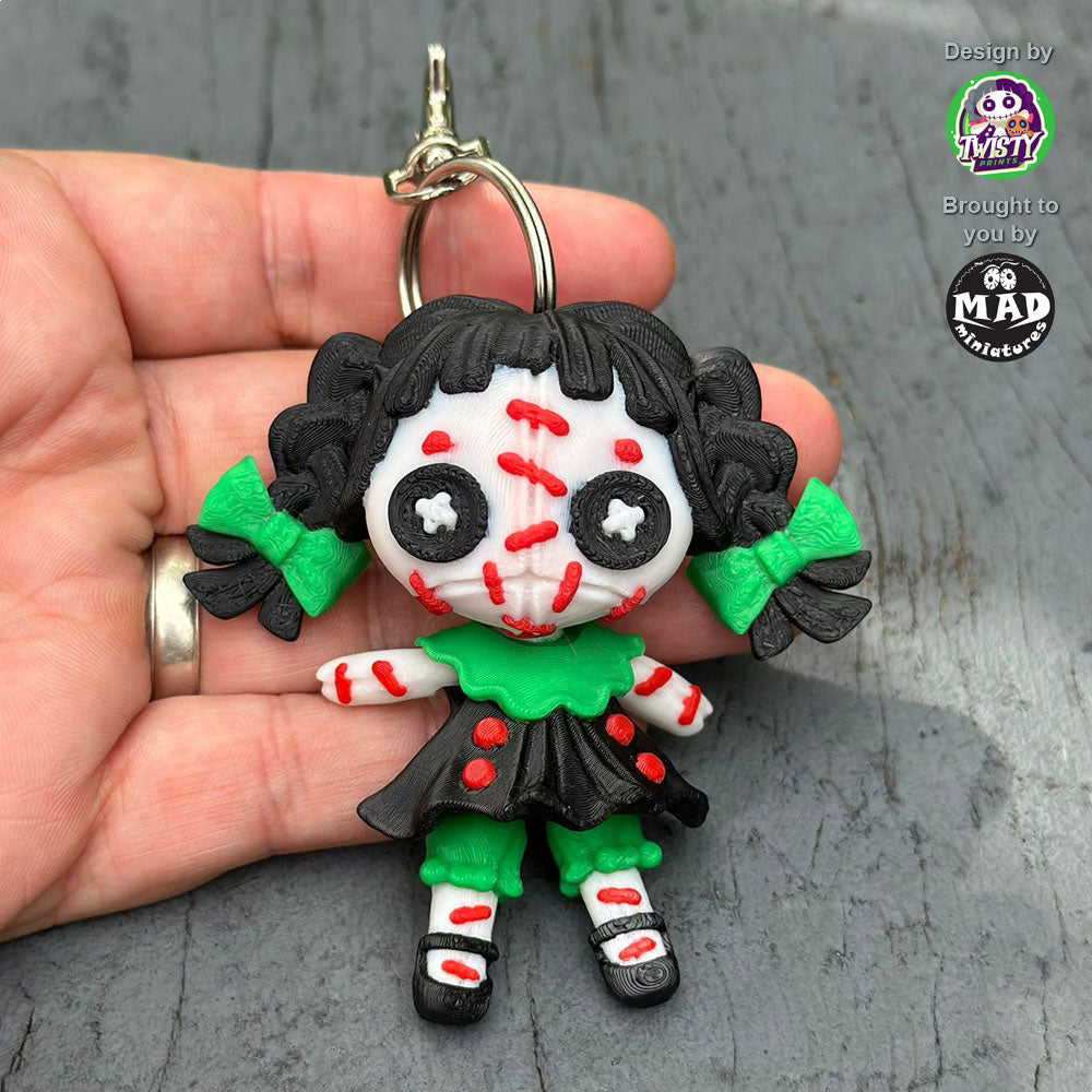Creepy Doll Keychain from Mad Miniatures, designed by Twisty Prints. A spooky and cute accessory with intricate details. Perfect for horror fans and keychain collectors.