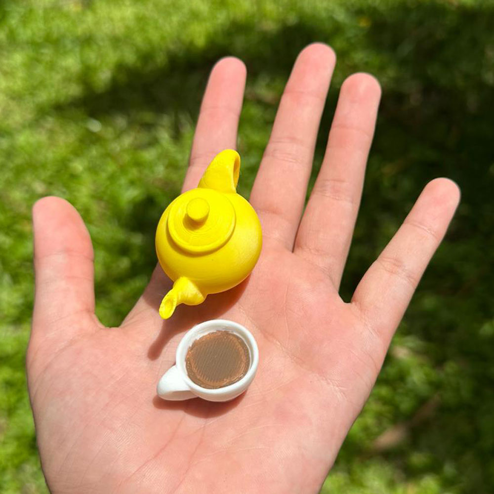 Close-up of the Mad Hatter’s teapot and cup, held in a person’s hand, perfect for a mad tea party