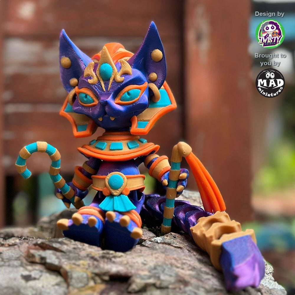 Pharaoh Cat sitting on a rock, displaying her elegant blue-purple shimmering coat, Egyptian ceremonial staff, and regal accessories.