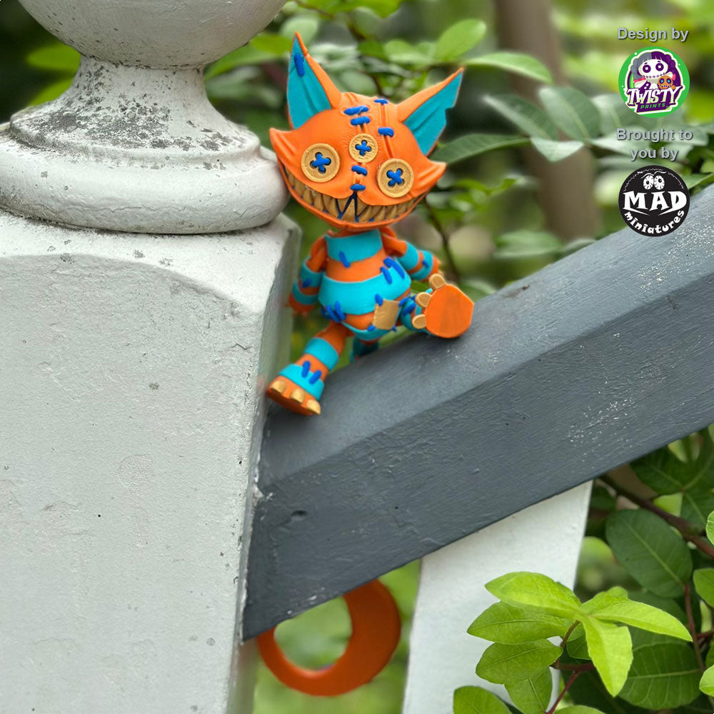 Stuffed Cat sitting on a balustrade, showing off her playful pose, vibrant orange and turquoise patchwork, and quirky charm.