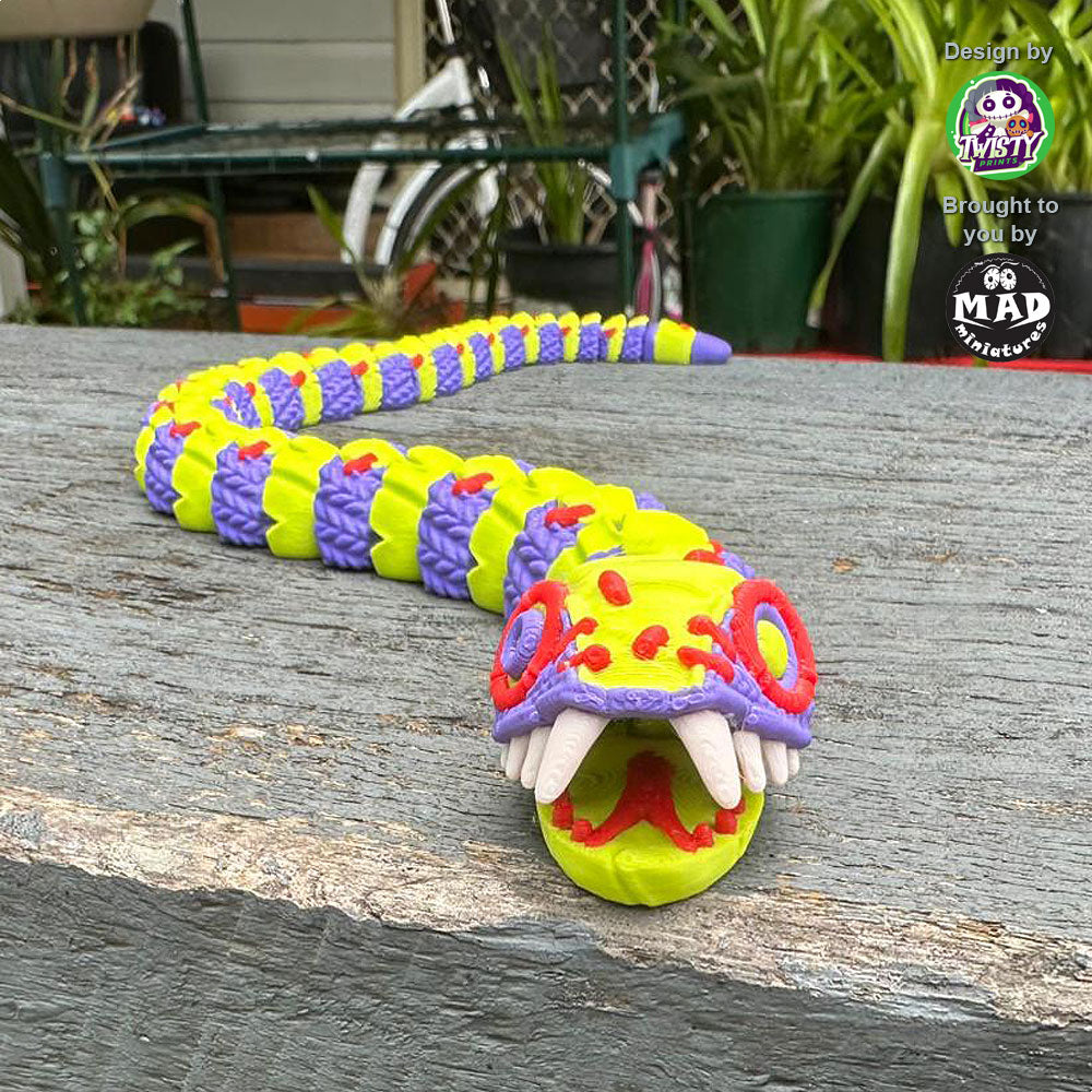 Big version of Stuffed Snake coming at you, highlighting the snake's bold purple and yellow-green body, contrasting stitches, and lifelike fangs.