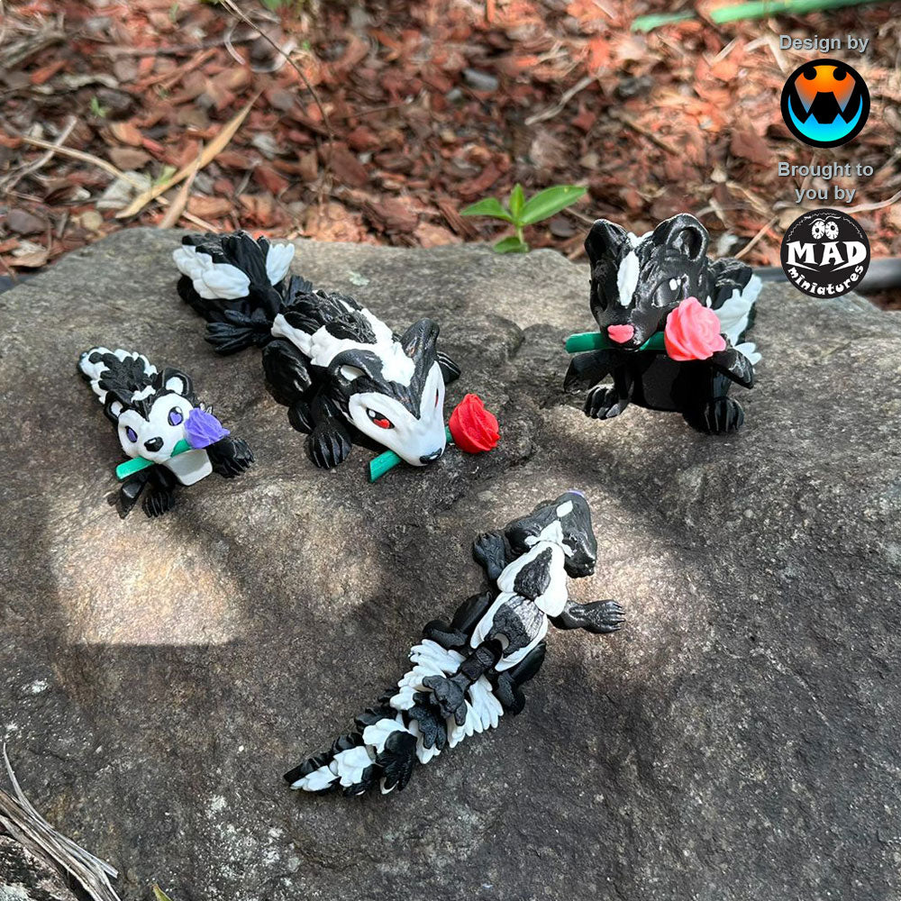 Cute Sweetheart Skunks from Mad Miniatures, designed by Cinderwing, on a rock, showcasing red, pink, and purple rose variations and one without a rose. Perfect for collectors.