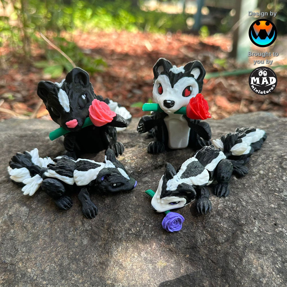 Four Sweetheart Skunks from Mad Miniatures, designed by Cinderwing, sitting on a rock. Featuring red, pink, and purple roses, and one without a rose. Adorable articulated collectibles.