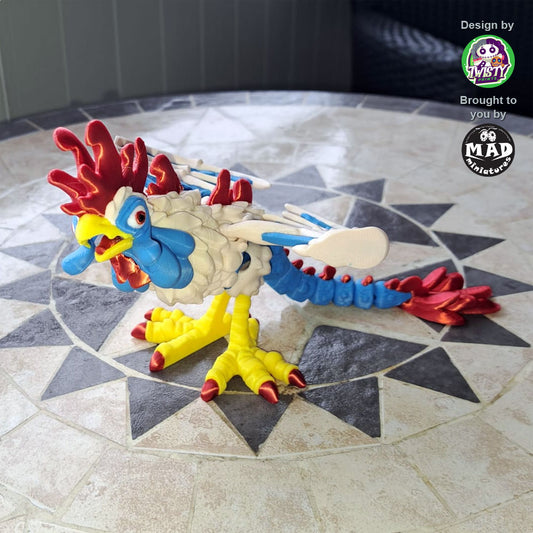 3D-printed articulated Cockatrice by Mad Miniatures in red, yellow, blue and green with detailed wings and claws, posed on a wooden base.