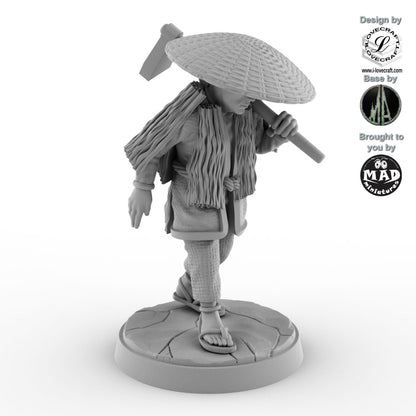 32 mm miniature of a Japanese farmer wearing a straw hat and cloak, carrying a hoe – Nippon Saga model by Mad Miniatures.